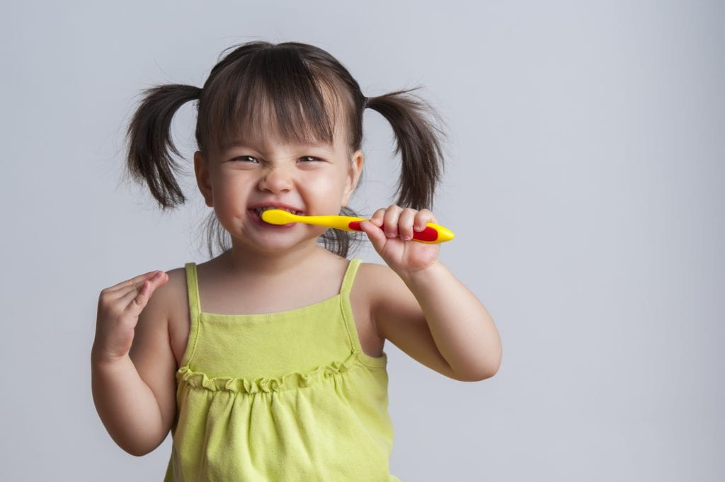 toddler smiling while brushing her teeth | Crane & Seager Orthodontics in Fort Collins and Loveland, CO